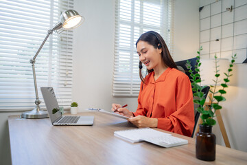 A professional-looking young woman, smiling brightly in a call center office, is wearing headphones and assisting customers with online communication, customer service, providing advice, and offering
