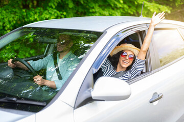 Excited young beautiful lady enjoying car trip with her boyfriend, wearing sunglasses and summer...