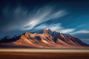 Long-exposure captures dramatic mountain range under a streaked blue and white sky