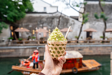 Young female tourist holding a jasmine ice cream, a local dessert at Pingjiang Road in Suzhou, China