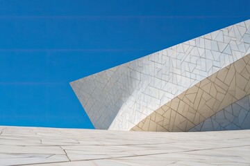 Modern architectural facade of angled, tiled structure against a bright blue sky