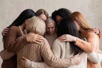 Multi generational women embracing an older woman in a circle of support