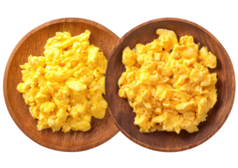Two wooden bowls hold fluffy, golden scrambled eggs against a black backdrop