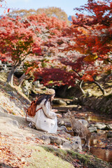 Young female tourist feeding deer in Nara Park during the autumn foliage