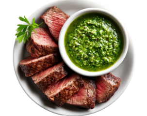 Sliced rare steak with green sauce, served on a white plate, garnished