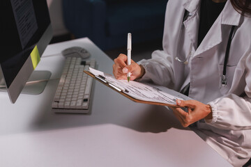 Doctor writing patient report on clipboard at desk