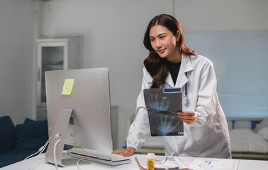 Female doctor analyzing hand x ray film on computer