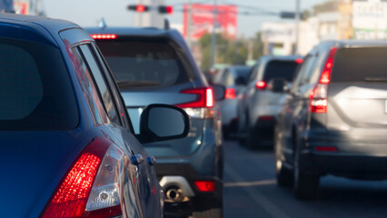 Rear side of blue car on asphalt road. With turn on brake light in traffic junction there are many cars on the road. Red traffic light ahead. Environment in the city of Thailand.