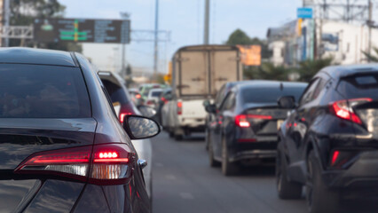 Rear side of cars on the asphalt road. Driving of many car in the business time in the city of Thailand. City with various advertising signs.