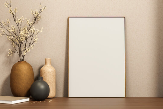 White drawing or photo frame leaning against wall with flower vases and book on wooden counter table