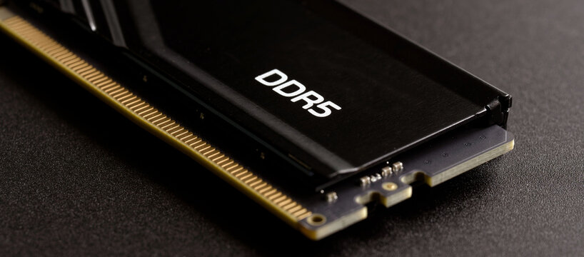 Fast DDR5 SDRAM stick for gaming PC upgrade. Macro shot of the connector pins and heat sink on a textured surface. Technology and hardware shortage concept. Photo