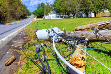 Utility pole down on rural road after storm cables scattered across grass pavement