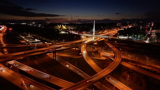 Aerial night view of Turcot Interchange in Montreal with glowing highways and city lights at dramatic blue hour. g.