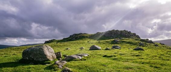 Boulder-strewn green hillside landscape under stormy sky, sunbeams breaking through clouds, rocky moorland scenery with dramatic light and wide horizon
