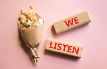 We listen symbol. Wooden blocks with words We listen. Beautiful pink background. Business and We listen concept. Copy space.