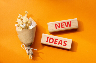 New ideas symbol. Concept word New ideas on wooden blocks. Beautiful orange background with bouquet of flowers. Business and New ideas concept. Copy space