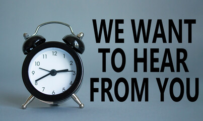 We want to hear from you symbol. Wooden blocks with words We want to hear from you. Beautiful grey background with alarm clock. Business and We want to hear from you. Copy space.