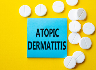 Atopic Dermatitis symbol. Concept word Atopic Dermatitis on blue note. Beautiful yellow background with pills. Medicine and Atopic Dermatitis concept. Copy space