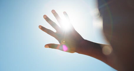 Person, outdoor and hand in sunshine with glare, eye protection and blue sky on holiday. Summer vacation, travel and tourist with shield for UV rays, lens flare and vision safety on nature trip © Flash25/peopleimages.com