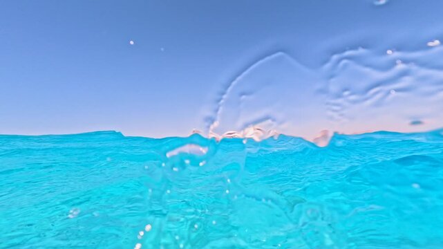 Dramatic half underwater wave rolling over camera with distant yachts on turquoise sea