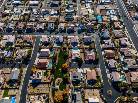 Wide aerial view of suburban residential neighborhood with swimming pools and grid streets in a dry desert city of the American Southwest