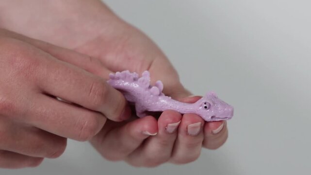 Close Up of Hands Stretching and Squishing a Purple Dinosaur Toy