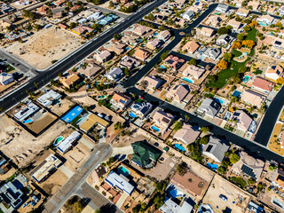Top down aerial view of suburban homes in Los Angeles with swimming pools, solar panels, detached houses and straight residential streets in a dry desert climate environment