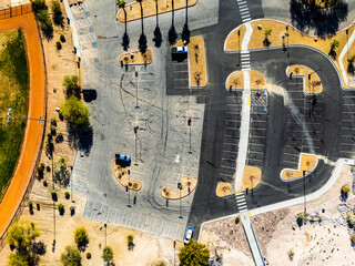 Aerial top view of large parking lot and public facility in suburban Los Angeles with marked parking spaces, pedestrian paths, dry surroundings and minimal vehicle traffic