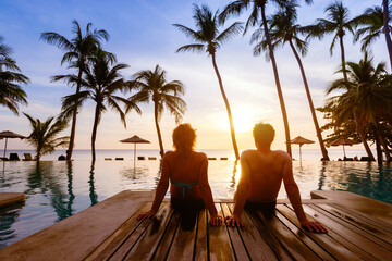 silhouette of couple sitting near swimming pool at beach hotel resort, summer holidays, honeymoon vacation travel to tropical country