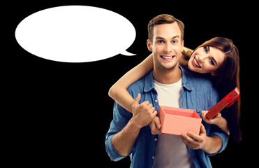 Big deals, discounts offers concept - expressive happy smiling cute young couple man woman open red gift box. Isolated black background with empty mockup speech bubble. Mock up ad image