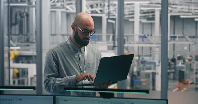 Engineer Tracking Production Process With Laptop. Experienced Male Specialist Auditing Production Flow and Metrics on thin laptop. Engineering Oversight, Digital Tools in Smart Manufacturing.