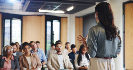Back of woman, audience and speaker with presentation, business conference and seminar event. Workshop, training and feedback summit with coach, sales education and crowd for career development © Flash25/peopleimages.com