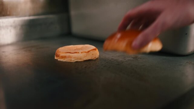 Chef toasts burger buns on hot commercial griddle