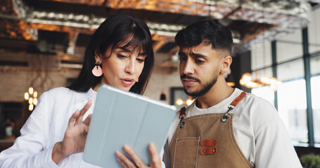 Owner, waiter and meeting with tablet for online inventory checklist, help with staff schedule or supplier info. Woman, man and restaurant team on tech for menu planning advice or problem solving