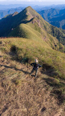Hiker with backpack reaches the summit of mountain peak. Success, freedom and happiness, achievement in mountains.