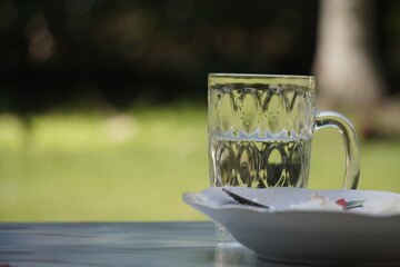 Glass Mug with Tea on Saucer Outdoors.