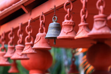 Sacred bells in a row hanging on the red Hindu temple ceiling, one bronze bell among red bells, Hyderabad, India.