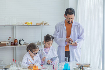Indian teacher give thumbs up to Adorable sibling primary school student kids girl in science class for good experiment method using modern technology tablet application, lifestyle education learning