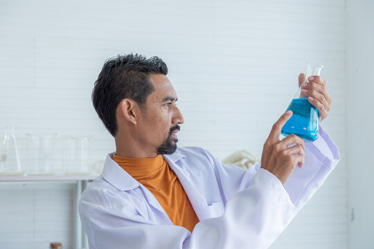 Scientist man holding test tube with color liquid. Laboratory assistant comparing samples in test tubes. Biochemistry or chemical research working in laboratory analyzing results of germ test in lab. - Powered by Adobe