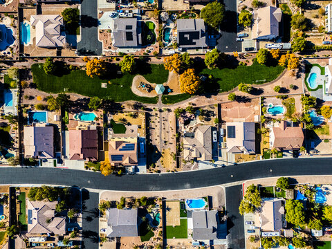 Top down aerial view of suburban homes in Los Angeles with swimming pools, solar panels, detached houses and straight residential streets in a dry desert climate environment