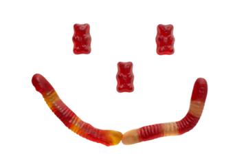 Smiling face made of red and orange gummy bears in playful mood with vibrant colors on white background for childrens party