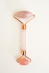 Pink jade roller for aesthetic facial massage on a white background. Rose quartz roller. Cosmetic tool