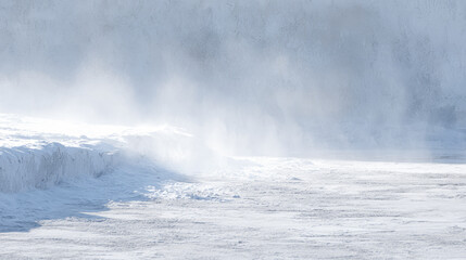 Snow covers ground while wind blows snow dust into the air in a cold area during wintertime