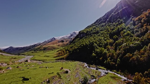 An aerial view from a quadcopter FPV drone of a civilian helicopter transporting cargo high in the mountains. Slingers tie cargo to the helicopter.