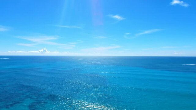 Bright sunny day over the turquoise ocean with a clear blue sky and some white clouds
