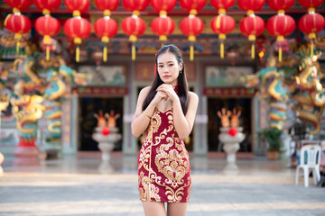 Portrait beautiful smiles Asian young woman wearing red cheongsam dress traditional decoration for Chinese new year festival celebrate culture of china at Chinese shrine Public places in Thailand