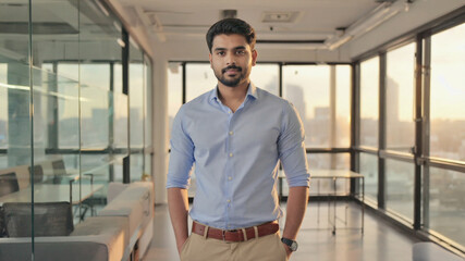 Young businessman in suit standing at workplace, young man standing calmly in modern office