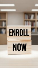 Wooden blocks with ENROLL NOW text on a table in a blurred office background