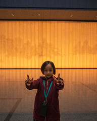 Little girl making peace sign while standing in the lobby of a museum. Travel education concept.