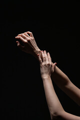 Artistic composition of two feminine hands in a delicate pose against a deep black background, highlighting natural form and subtle lighting